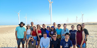 Photo of the group on the beach in front of many wind turbines
