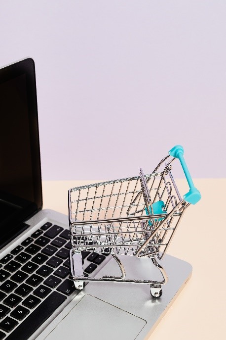There is a small shopping cart on top of a laptop.