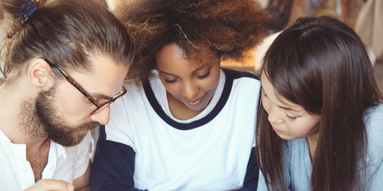 Students Documents Three students put their heads together over documents.